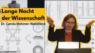 Dr. Carola Metzner-Nebelsick spricht bei der "Langen Nacht der Wissenschaft" 2026. Sie gestikuliert mit beiden Händen vor einem Bildschirm, der verschiedene wissenschaftliche Symbole und Objekte zeigt. Hinter ihr ist eine grafische Darstellung von Gegenständen zu sehen.