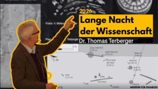 Ein Mann mit Brille und grauem Haar, Dr. Thomas Terberger, zeigt auf eine grafische Darstellung während der "Langen Nacht der Wissenschaft" 2026. Im Hintergrund sind archäologische Abbildungen und Informationen zu sehen.