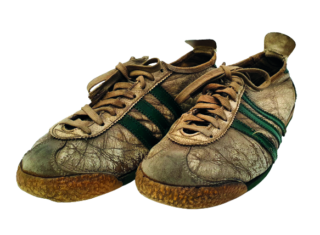 Ein Paar abgenutzte Sneaker in Grautönen mit grünen Streifen und einer rutschfesten Sohle, auf einem weißen Hintergrund platziert.