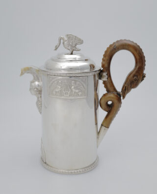 Ein Gefäß aus Silber, dessen Deckel eine Schwanenfigur ziert. Der Griff an der Seite stellt Kopf und Hals eines Schwans dar.